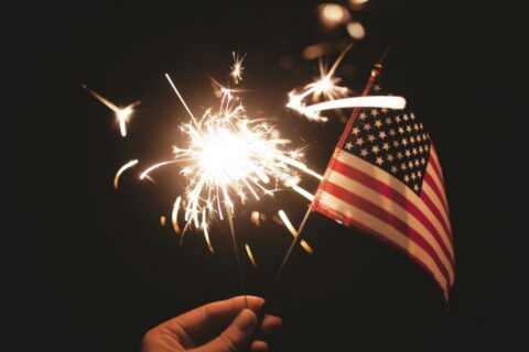 election-day Hand holding a sparkler and a small American flag (Photo by Stephanie McCabe on Unsplash)